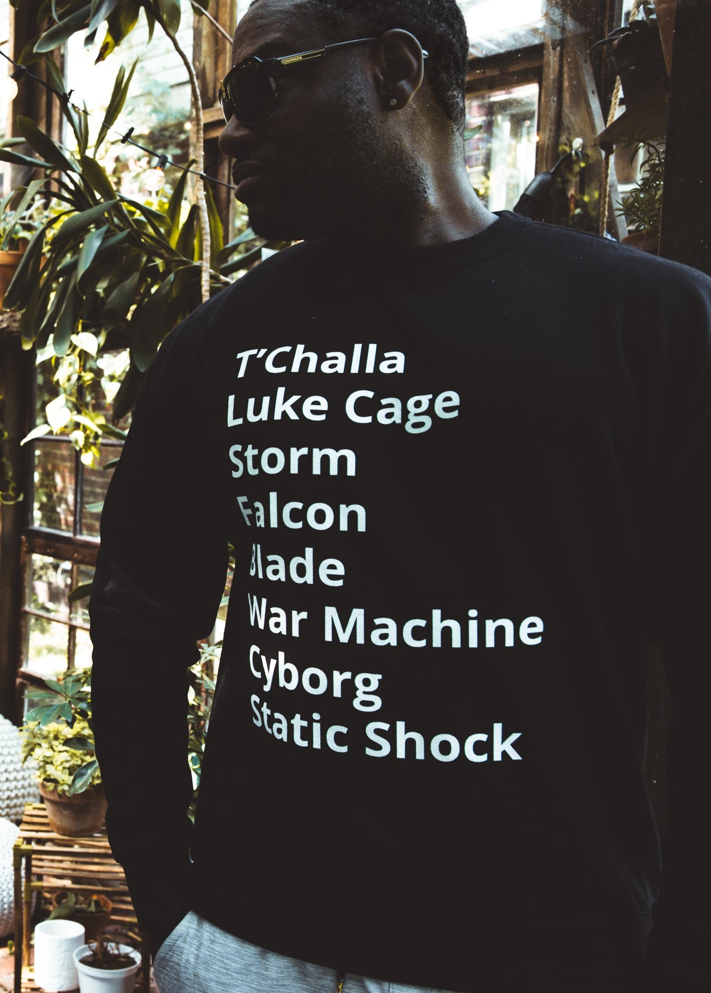 man wearing crew neck sweater with minimalist typography listing Black (African American) Super heroes from marvel and dc: T'Challa (Black Panther), Luke Cage, Storm, Falcon, Blade, War Machine, Cyborg, Static Shock.